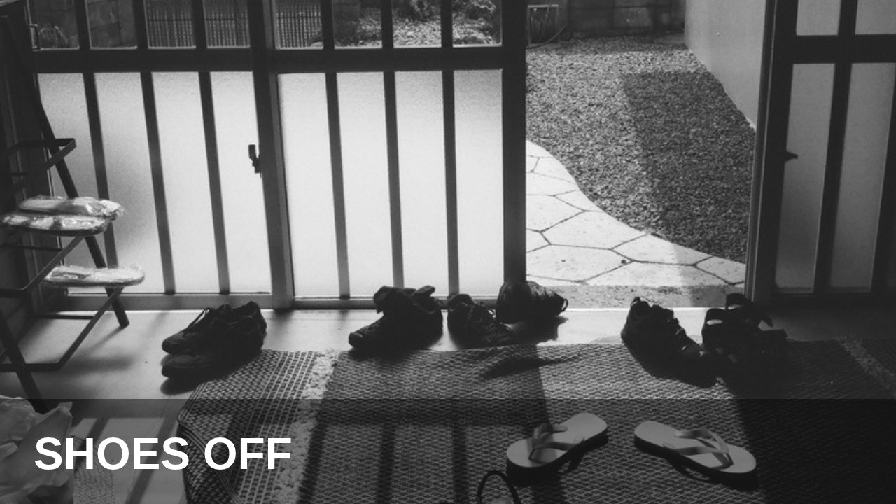 Shoes and sandals left on a mat at the entrance of a Japanese house